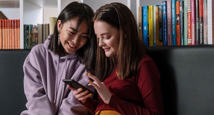 a photo of two teenage girls smiling and looking at a phone