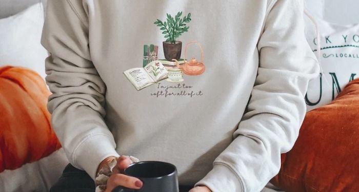 a sweatshirt with books, tea kettle, and plants on it that reads "I'm just too soft for all of it"