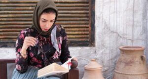 fair-skinned woman in headscarf reading a book