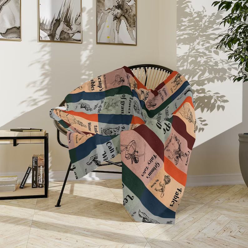 Photo of a very colourful blanket open over a chair featuring the covers of classical books like Alice In Wonderland making it look almost like a quilt