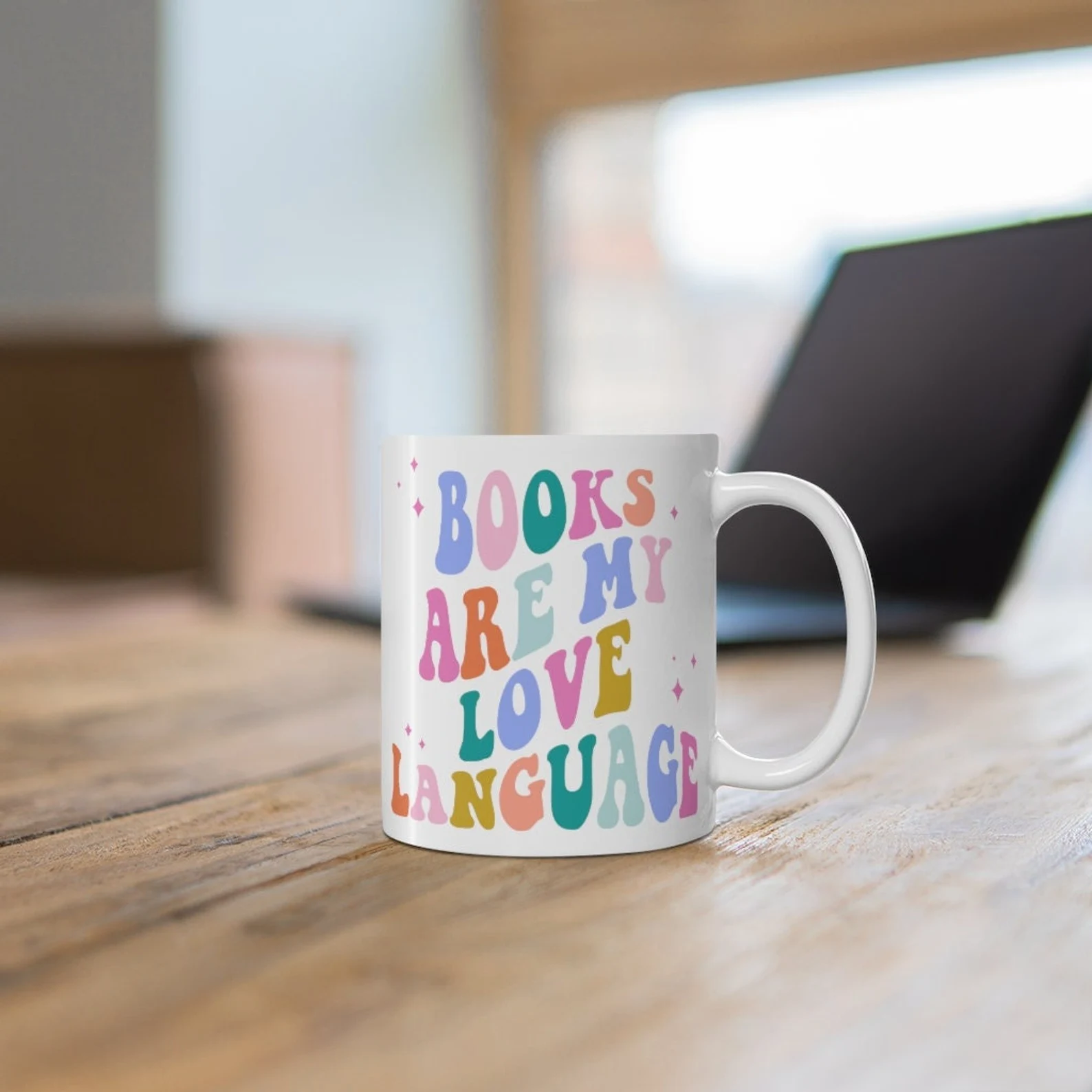 white mug with retro 70's font in pink, orange, blue, green, and gold lettering the reads "books are my love language"