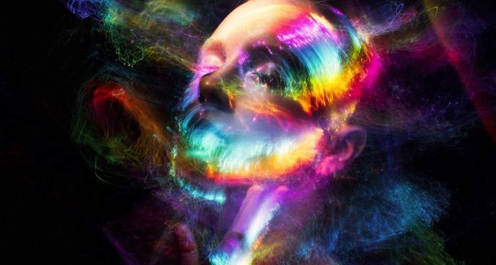 a person's face surrounded by splashes of light in neon rainbow colors