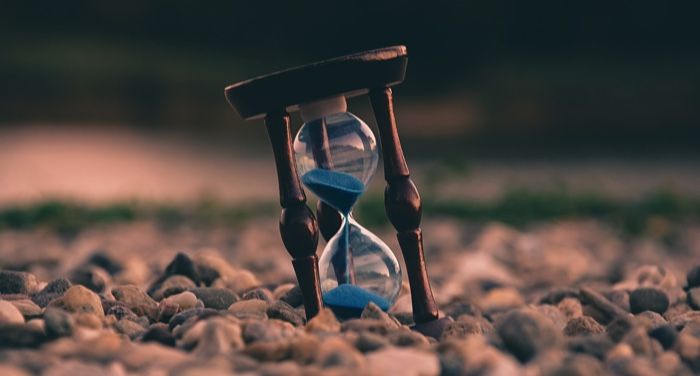 hourglass with blue sand sitting on rocks