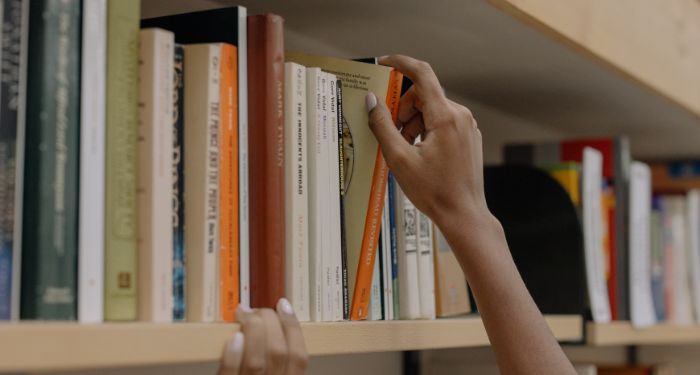 Image of a hand pulling a book off a shelf