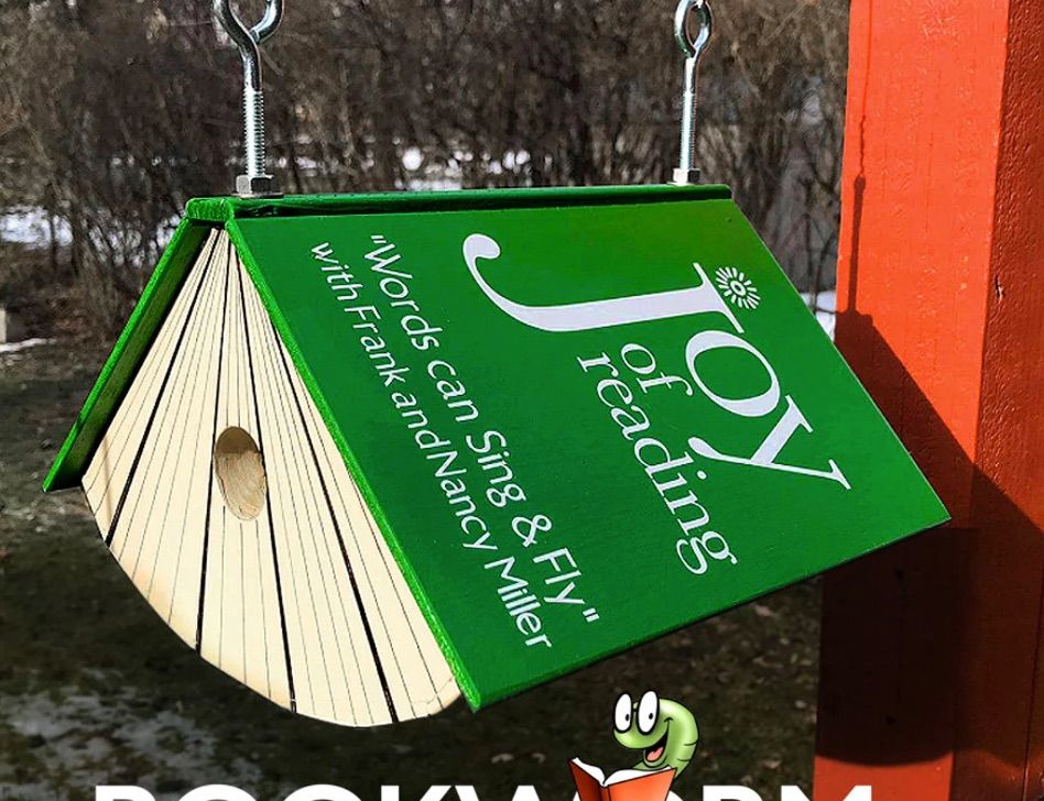 Image of a green birdhouse in the shape of a book. The book is titled 