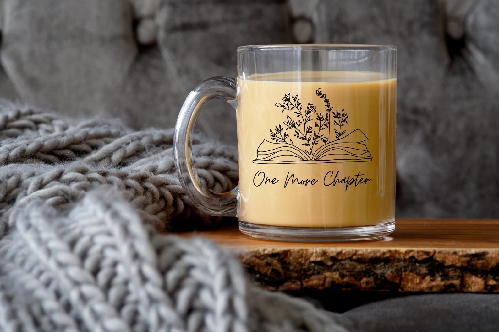 Glass mug with line art of an open book and flowers that reads "one more chapter"