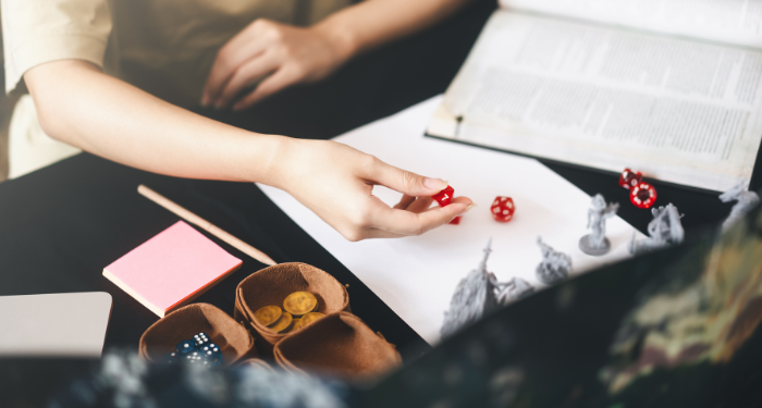 a photo of someone rolling a D20 behind a DM screen