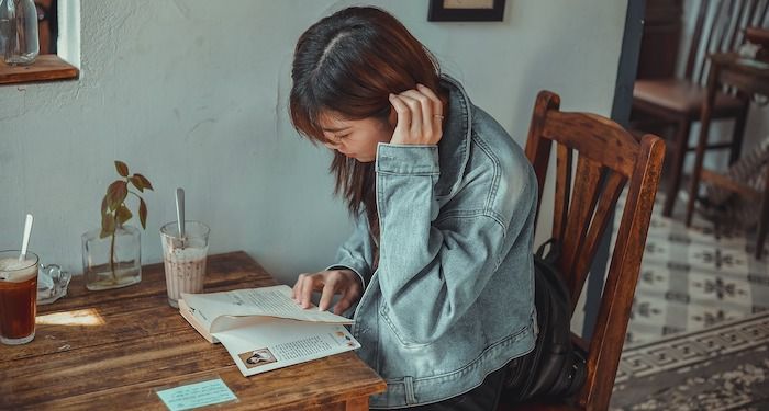 a photo of a woman reading at a cafe