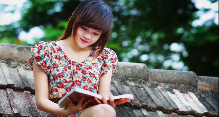 light-skinned Asian girl reading on roof