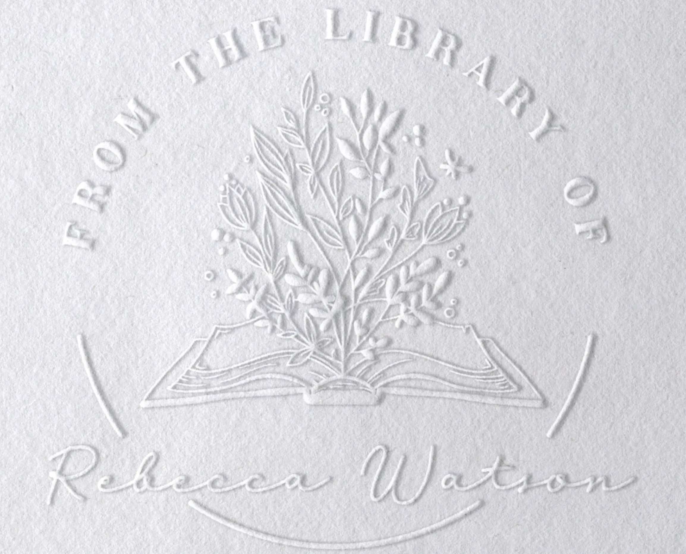 A white page with an embossed book and flowers. the text says "From the library of Rebecca Watson"