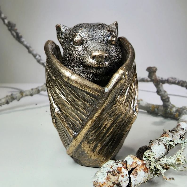a photo of a bronze trinket cup in the shape of a bat with its wings curled in