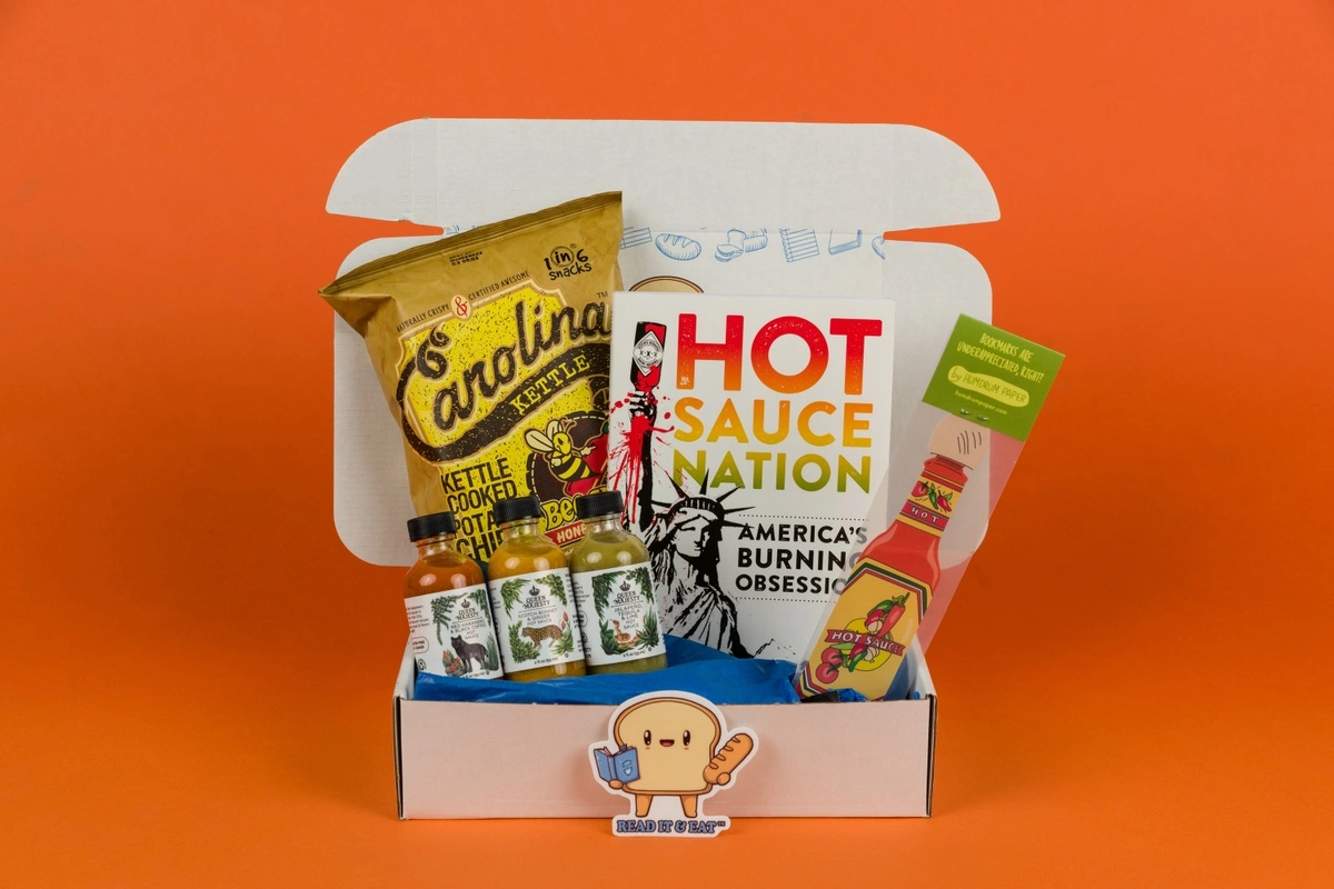 a photo of a Read It and Eat subscription box with the book Hot Sauce Nation and several hot sauces and spicy snacks