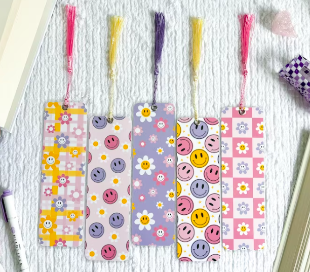 Image of five pastel tasseled bookmarks with retro flower and smiley face patterns