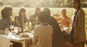 a group of people of different ethnicities gathered drinking wine and eating