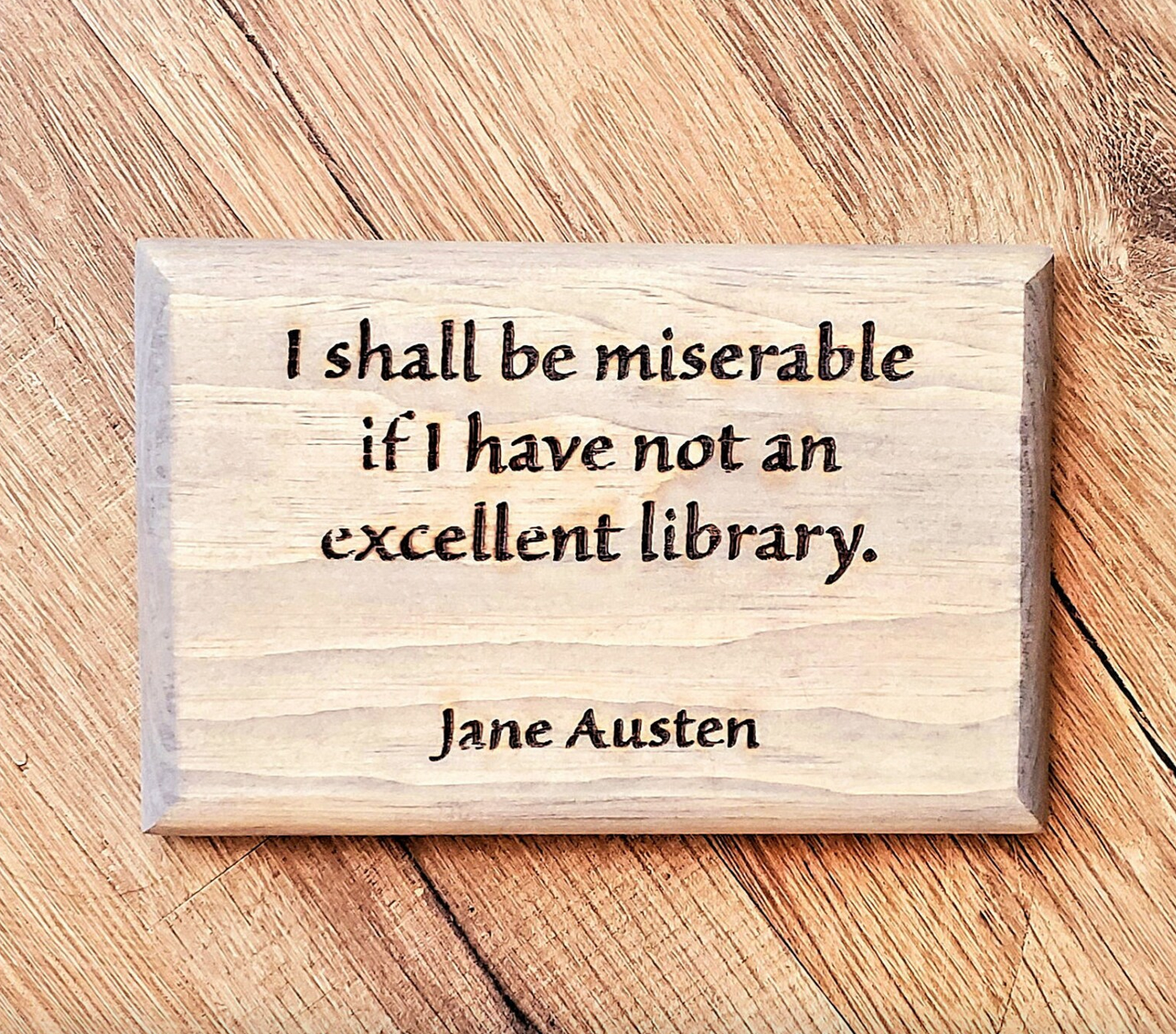 A wooden sign with the text "I shall be miserable if I have not an excellent library. Jane Austen"