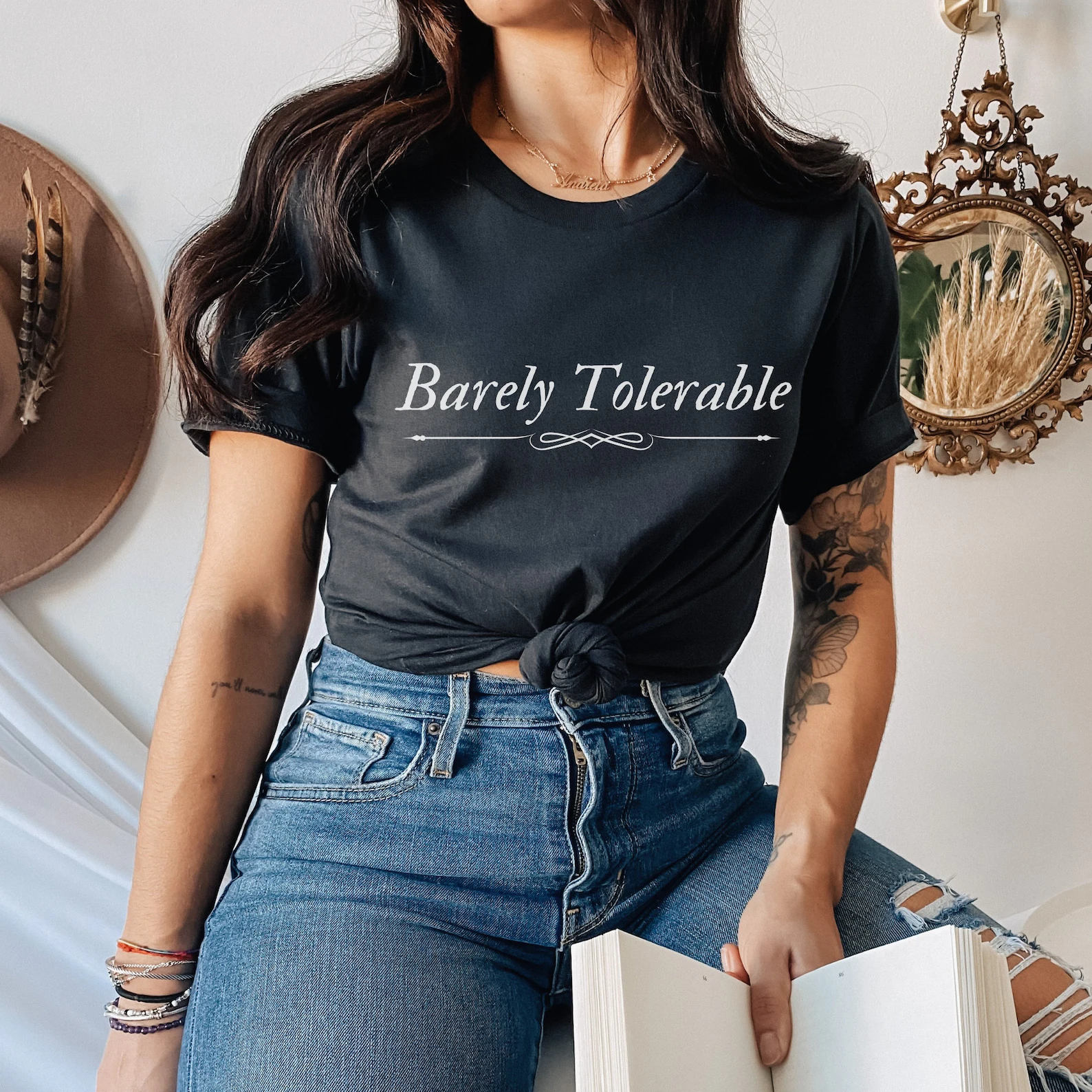 A black t-shirt with the words "Barely tolerable;e" written in fancy font