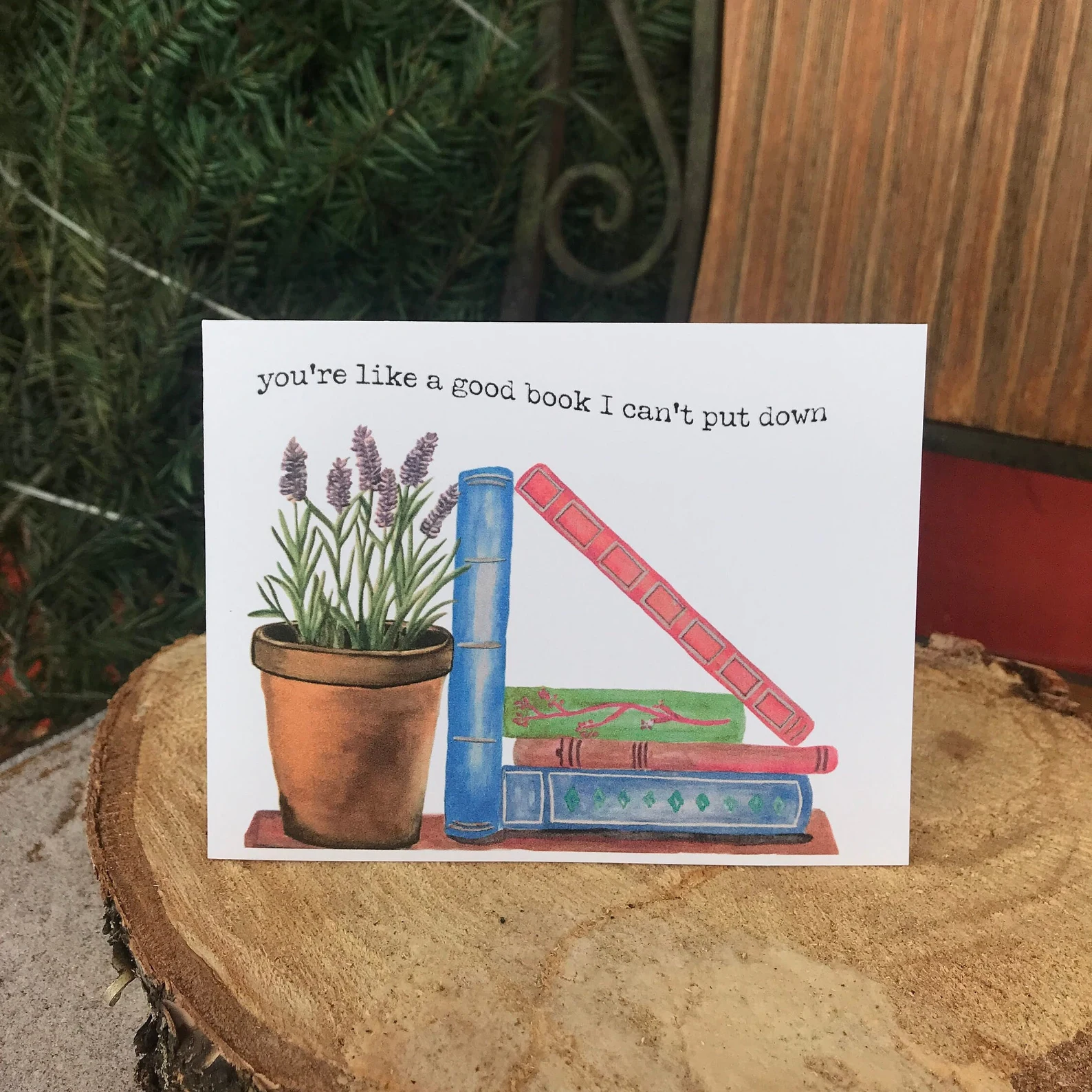 A card portraying a stack of books and a pot of lavender and the works "You're like a good book I can't put down"