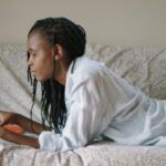 Image of a Black woman reading on a couch