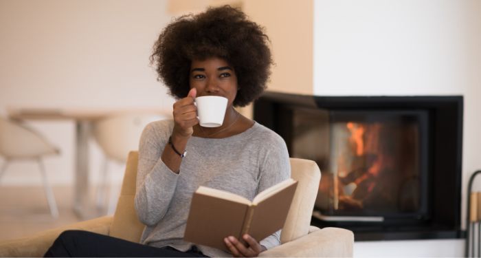 image of a Black woman reading with a cup of coffee