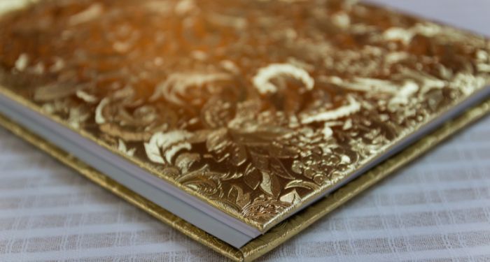 book with golden hardcover with flower tracery on a white tablecloth