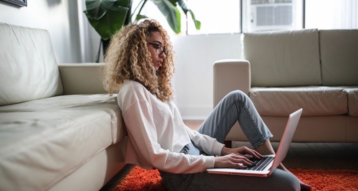 light tan-skinned woman with kinky curly blonde hair on laptop; photo by thoughtcatalog.com