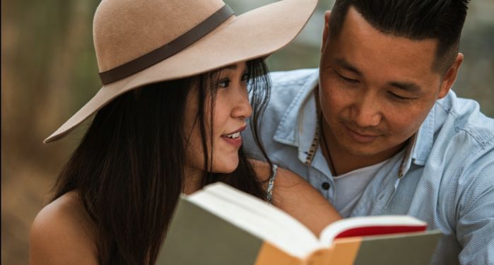 tanned-skinned Asian man and woman looking at a book