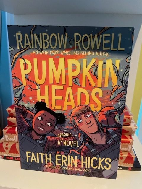 Pumpkinheads on a bookshelf with a stack of gift wrapped books behind it