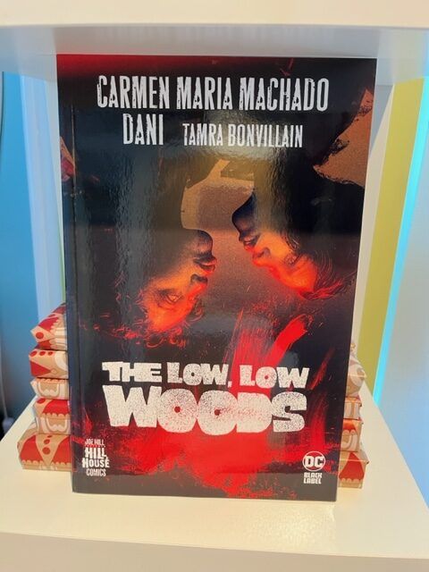 The Low Low Woods on a bookshelf with a stack of giftwrapped comics behind it