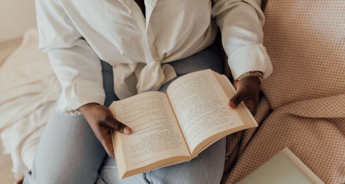 dark brown skinned woman holding book open to read