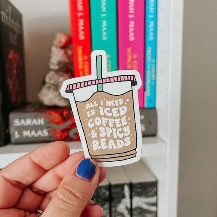 sticker in the shape of an iced coffee cup with bubble letters that read "All I need is iced coffee and spicy reads."