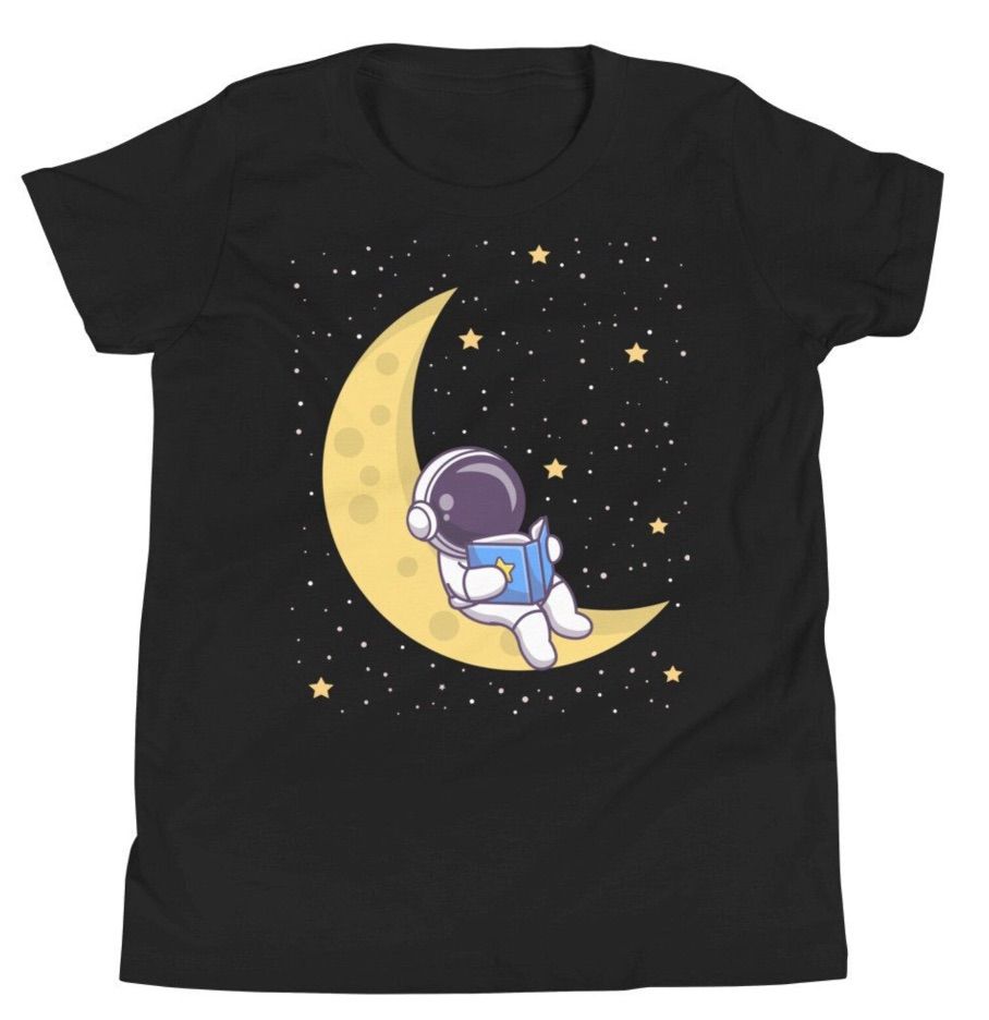 Image of a black t-shirt with an astronaut reading a book on a crescent moon. 