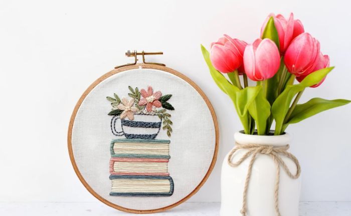 book stack embroidery hoop next to a vase of pink tulips