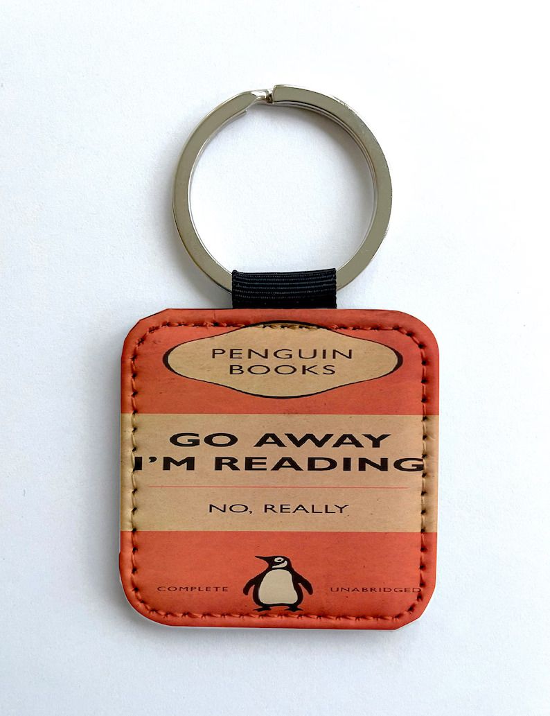 Photo of a keychain with the cover of a penguin classic with the text Go away I'm reading in the middle, and below in smaller letter No, really. 