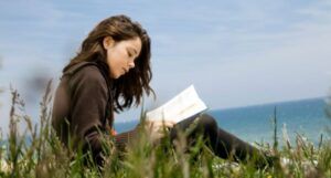 Image of a person with long brown hair reading on a beach