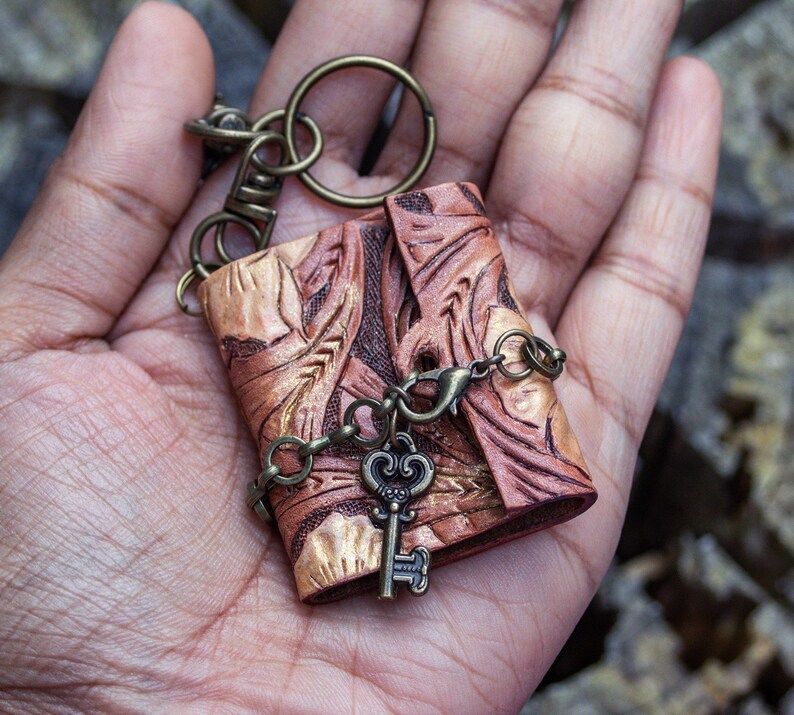 Photo of a small leather-bound notebook keychain with a small metal key dangling from the opening.