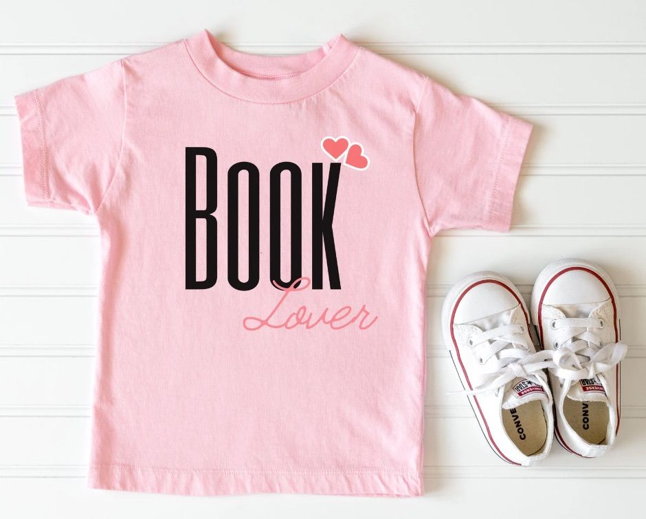 Image of a pink t-shirt. It has BOOK written in black letters and LOVER in a pink script. 