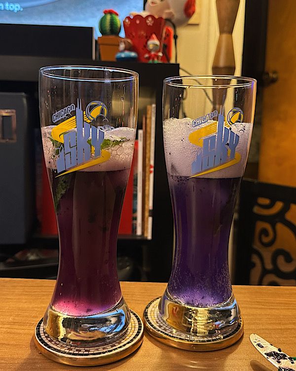Two glasses filled with liquid, one with a pink liquid and the other with a dark purple liquid