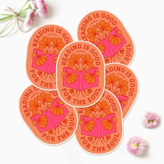 orange and pink oval sticker with books and flowers that says "reading is good for the soul."