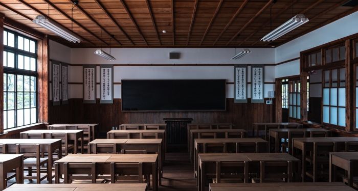 four rows of desks in a classroom with a black chalboard at the front