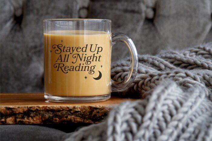glass mug with black lettering that reads "stayed up all night reading" with a black moon and stars 