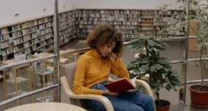 tan-skinned young Black woman or teen reading in a library
