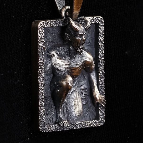 A rectangular pendant with an image of Lucifer climbing out of the center.