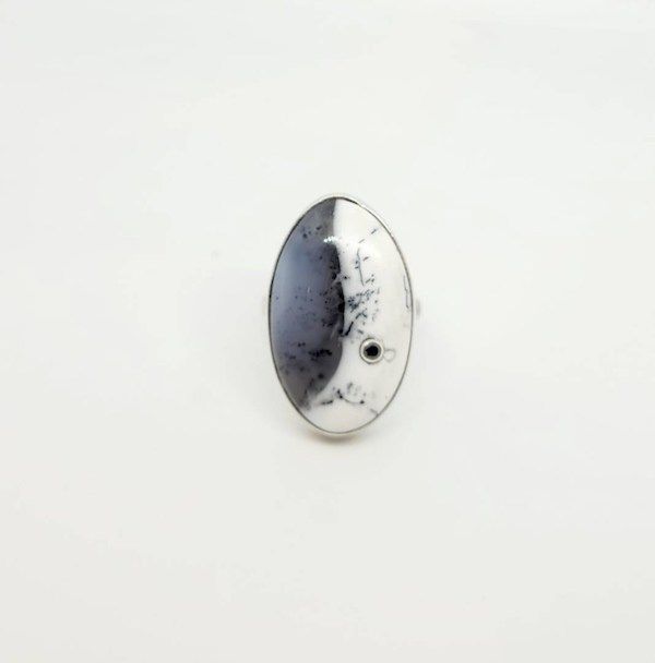 A silver ring set with a black and white stone inlaid with a small black diamond.