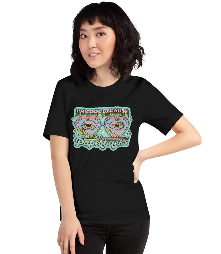 Image of a person with light skin wearing a black shirt. It includes heart-shaped sunglasses and eyes behind them in pastel colors. The text sys "I'm cool because I read paperbacks."
