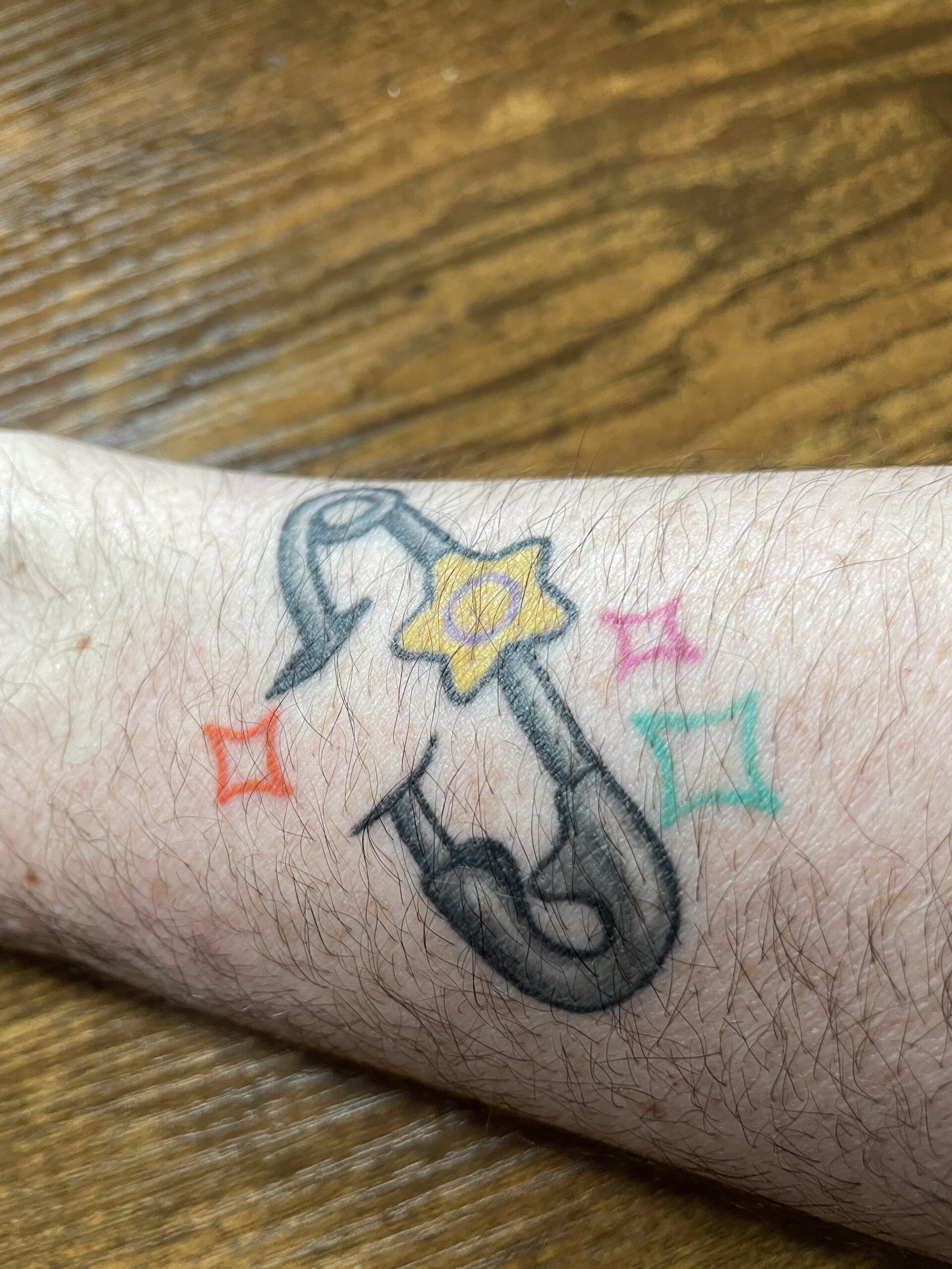 image of safety pin with intersex symbol tattoo