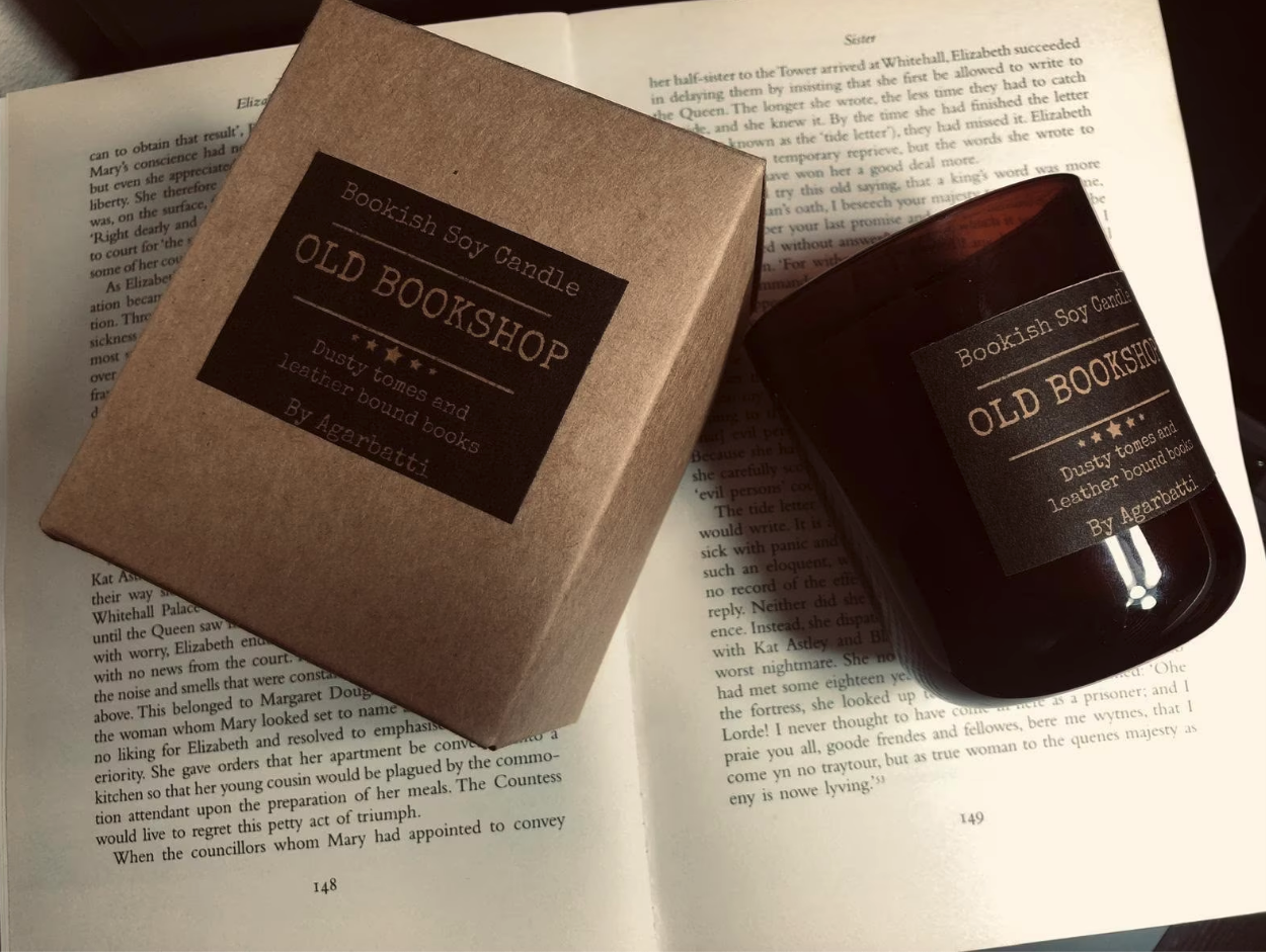 a candle and its box resting on an open book, with the text old bookshop on the candle