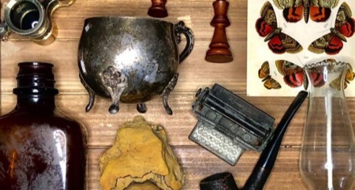 A flay lay of some dark academia knick knacks including chess pieces, a pipe, amber bottles, and more