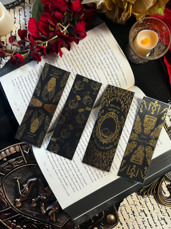Four black and gold flaked bookmarks placed on top of an open book