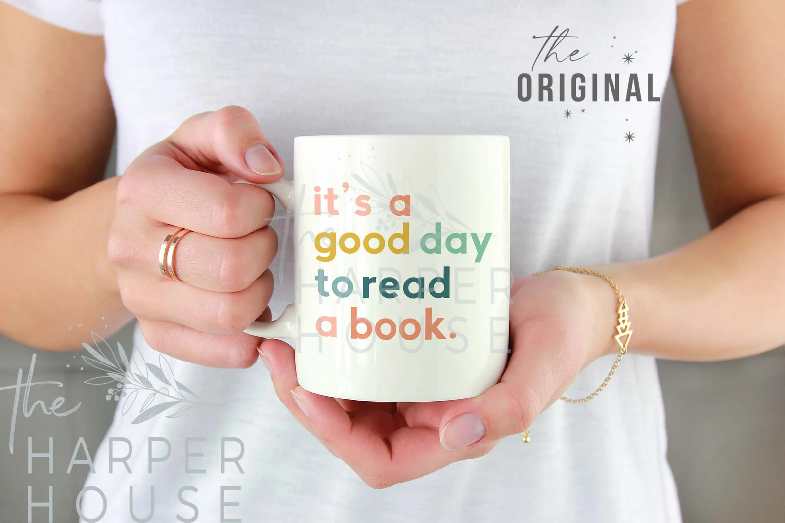 A white mug with the words "it's a good day to read a book" in pastel rainbow text