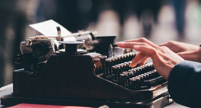 hands typing on an old-fashioned typewriter